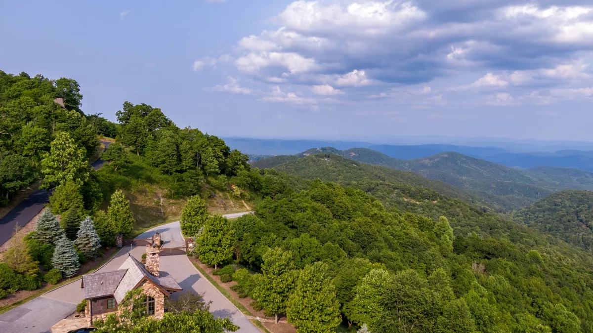 A breathtaking view of the Blue Ridge Mountains with lush greenery, a winding road, and stone architecture set against a serene sky. The expansive landscape invites exploration and adventure.