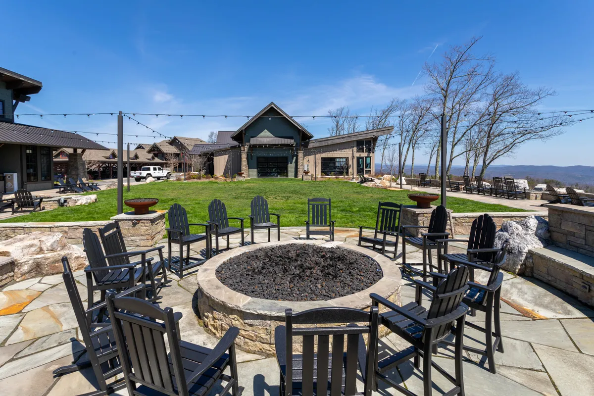 A welcoming fire pit surrounded by comfortable seating on a landscaped lawn with buildings in the background, creating a communal outdoor gathering spot perfect for winding down after a day of adventure.